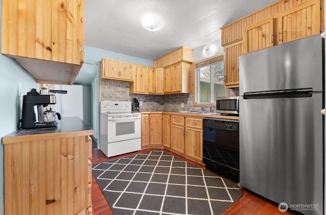 kitchen with dark wood-style floors, a sink, tasteful backsplash, light brown cabinets, and appliances with stainless steel finishes