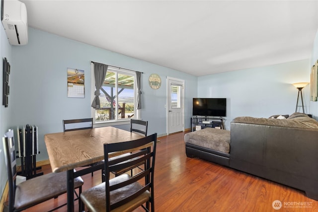 dining area featuring wood finished floors and a wall mounted AC