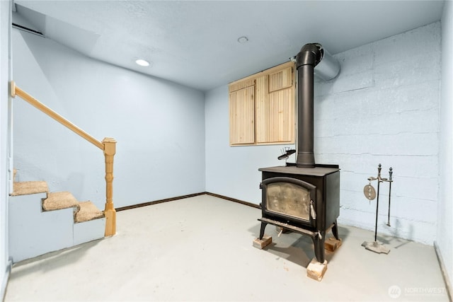 unfurnished room featuring recessed lighting, stairway, a wood stove, and finished concrete floors