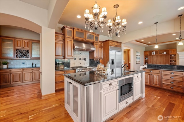 8131 116th Ave NE, Kirkland, WA 98033 - kitchen featuring a sink, built in appliances, arched walkways, brown cabinetry, and wall chimney exhaust hood