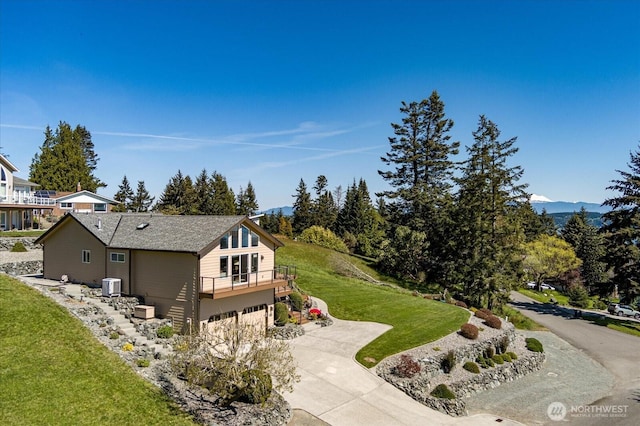 exterior space featuring central AC, concrete driveway, a front lawn, a mountain view, and a garage