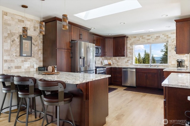 kitchen with a peninsula, appliances with stainless steel finishes, a skylight, and decorative backsplash