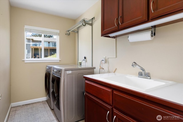 washroom featuring baseboards, a sink, washer and clothes dryer, and cabinet space