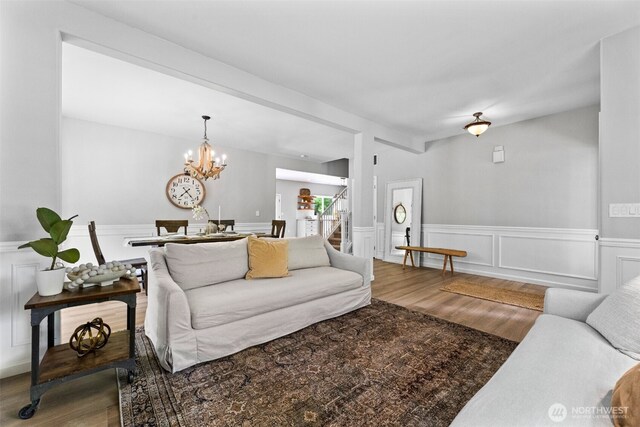 8203 32nd Ave E, Tacoma, WA 98443 - living area featuring wood finished floors, a chandelier, a wainscoted wall, stairway, and a decorative wall