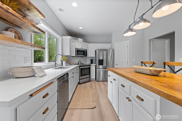 8203 32nd Ave E, Tacoma, WA 98443 - kitchen featuring stainless steel appliances, a sink, open shelves, light wood finished floors, and decorative backsplash