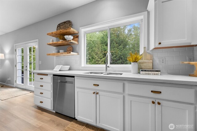 8203 32nd Ave E, Tacoma, WA 98443 - kitchen with dishwasher, a sink, light wood-type flooring, light countertops, and white cabinets
