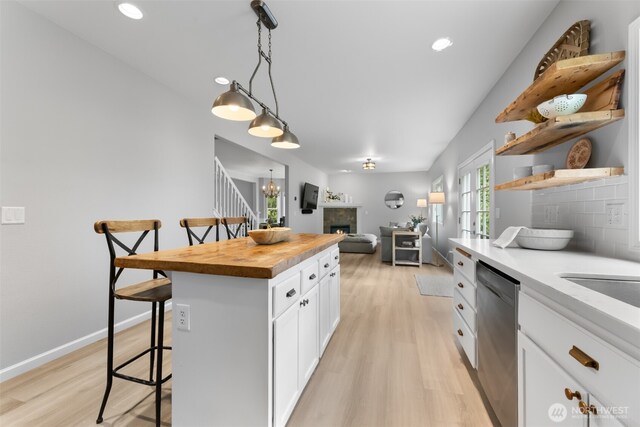 8203 32nd Ave E, Tacoma, WA 98443 - kitchen featuring stainless steel dishwasher, wooden counters, a breakfast bar, open shelves, and light wood-style floors