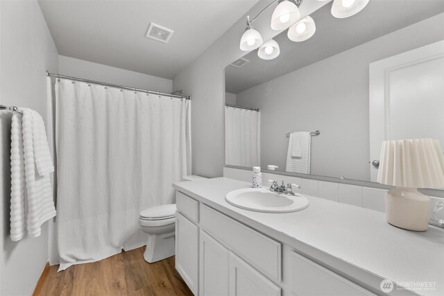 8203 32nd Ave E, Tacoma, WA 98443 - full bathroom featuring toilet, vanity, wood finished floors, and a shower with shower curtain