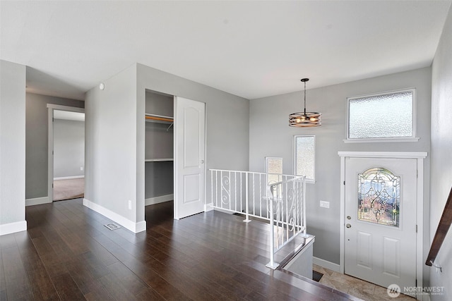 foyer featuring baseboards, a notable chandelier, and wood finished floors