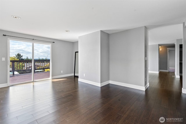 spare room featuring baseboards, dark wood-type flooring, and recessed lighting