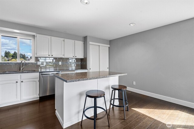 kitchen featuring decorative backsplash, stainless steel dishwasher, a sink, and dark wood-style flooring