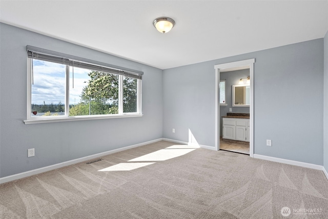 unfurnished bedroom featuring carpet flooring, baseboards, and connected bathroom