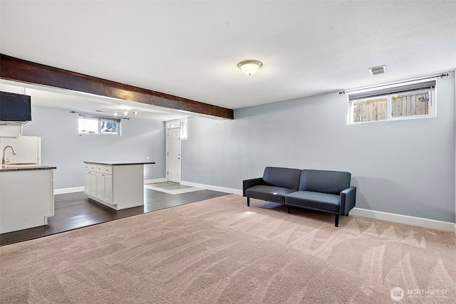 sitting room featuring plenty of natural light, baseboards, visible vents, and dark carpet