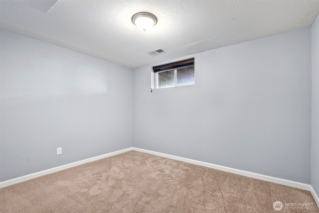 basement with baseboards, visible vents, carpet floors, and a textured ceiling