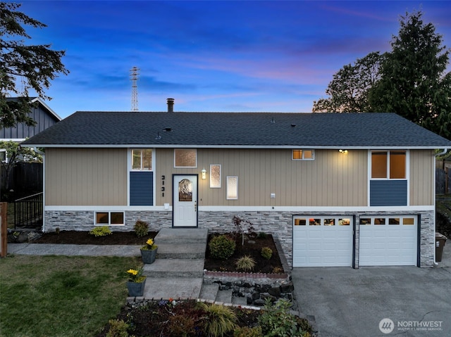 view of front of home with concrete driveway, stone siding, a shingled roof, and a garage
