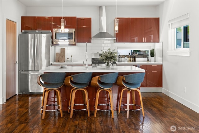 kitchen with decorative backsplash, an island with sink, modern cabinets, wall chimney exhaust hood, and appliances with stainless steel finishes