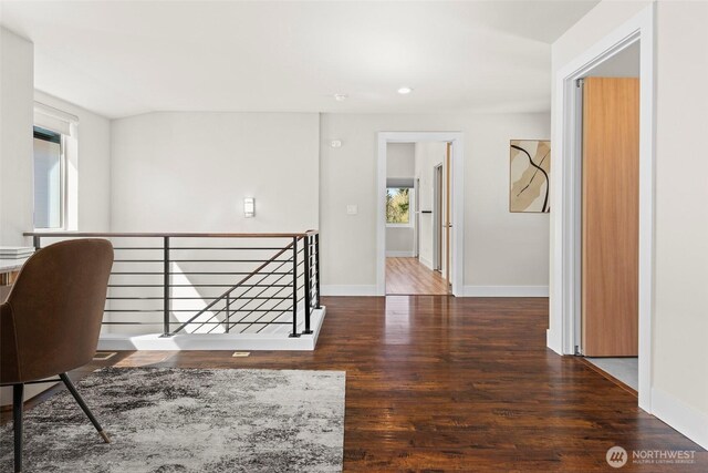 hallway featuring baseboards, wood finished floors, an upstairs landing, and recessed lighting