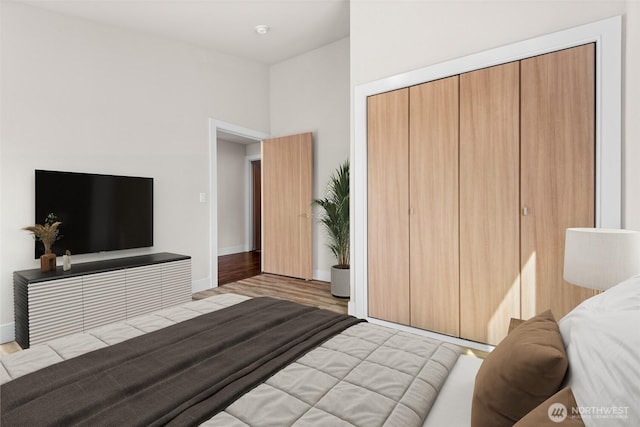 bedroom with baseboards, wood finished floors, and a closet
