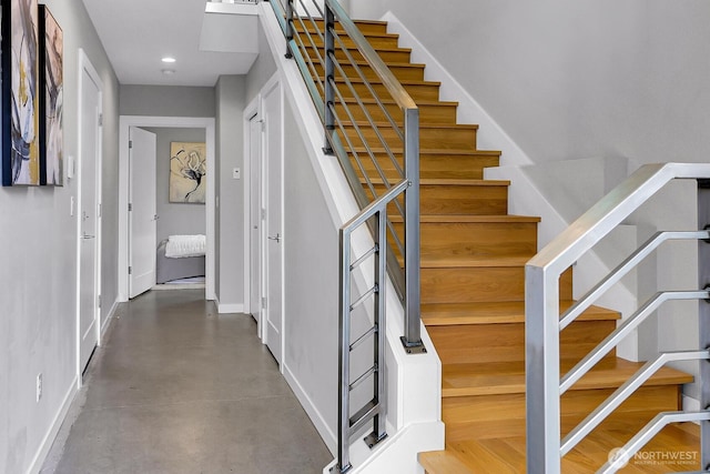 stairs featuring baseboards, finished concrete flooring, and recessed lighting