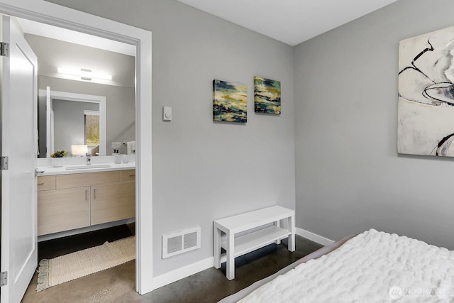bedroom with a sink, baseboards, connected bathroom, and finished concrete flooring
