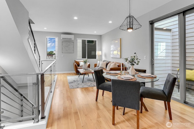 dining room with an AC wall unit, stairway, light wood-style floors, recessed lighting, and baseboards