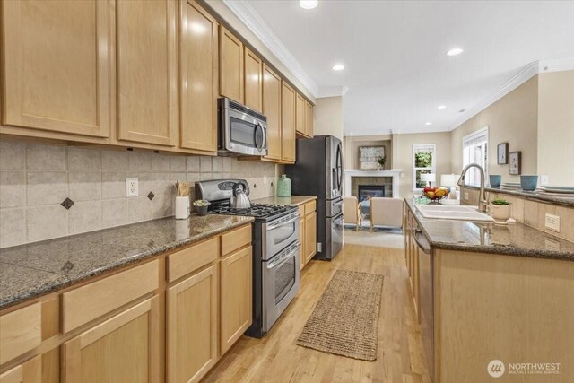 19017 5th St E, Lake Tapps, WA 98391 - kitchen with stainless steel appliances, a sink, crown molding, light wood-style flooring, and a glass covered fireplace