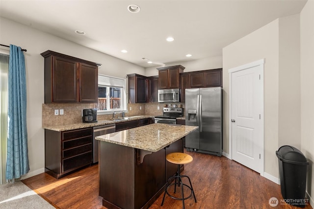 kitchen featuring stainless steel appliances, dark brown cabinets, backsplash, a kitchen island, and recessed lighting