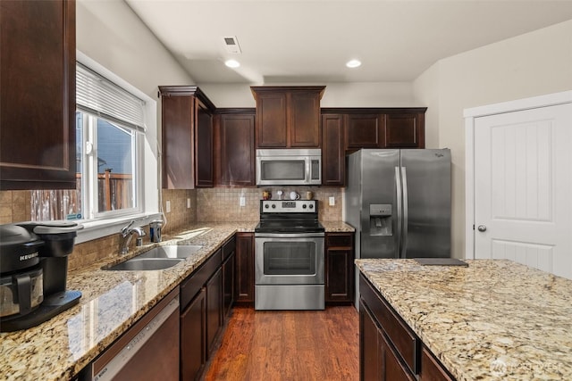 kitchen featuring stainless steel appliances, a sink, light stone countertops, decorative backsplash, and recessed lighting