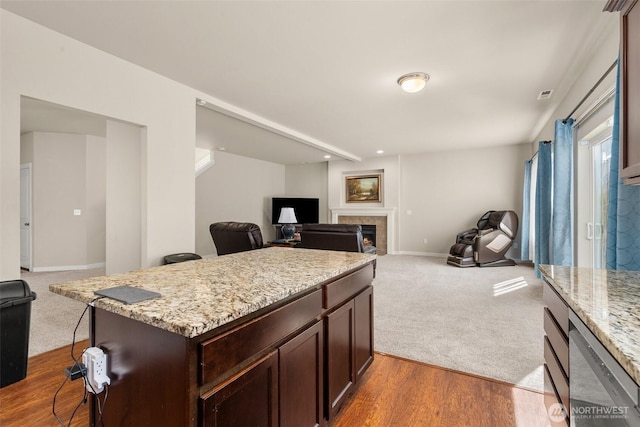 kitchen with open floor plan, dishwasher, a fireplace, dark brown cabinets, and baseboards