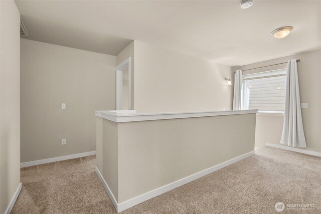 hallway featuring carpet and baseboards