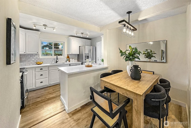 12910 6th Ave S, Burien, WA 98168 - kitchen with a sink, tasteful backsplash, white cabinetry, a textured ceiling, and appliances with stainless steel finishes