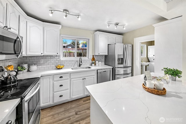 12910 6th Ave S, Burien, WA 98168 - kitchen with tasteful backsplash, light wood-style flooring, white cabinets, a sink, and stainless steel appliances