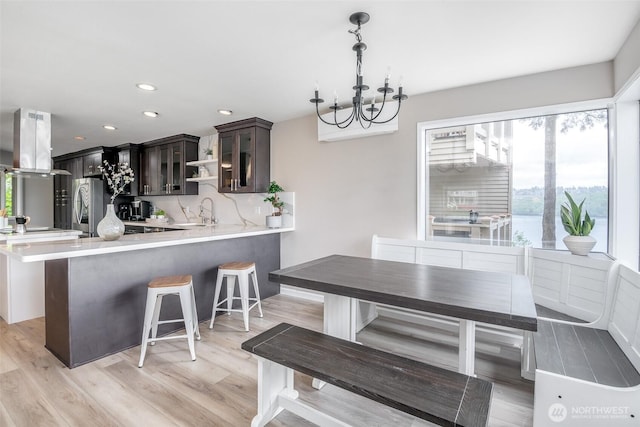 dining space with recessed lighting, a notable chandelier, and light wood-style flooring