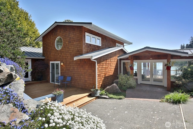 rear view of house with french doors, a deck, a standing seam roof, and metal roof