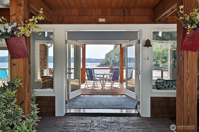 doorway featuring stone tile flooring, wood walls, and wooden ceiling