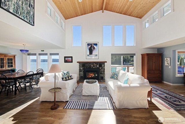living area with beam ceiling, wood finished floors, high vaulted ceiling, wood ceiling, and a tiled fireplace