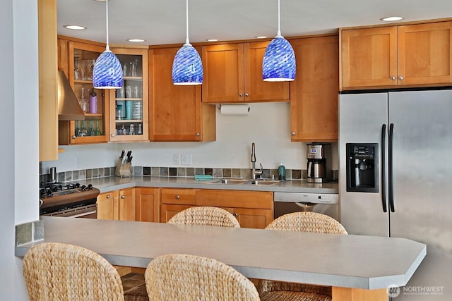 kitchen with pendant lighting, glass insert cabinets, recessed lighting, a sink, and appliances with stainless steel finishes
