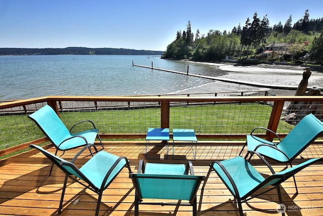 wooden terrace with a water view and a yard