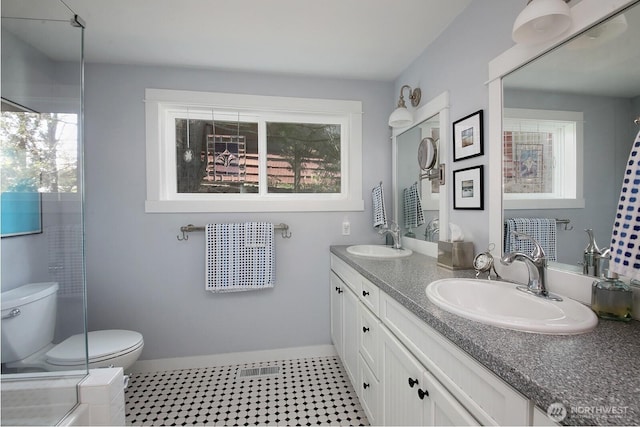 full bathroom with double vanity, toilet, baseboards, and a sink