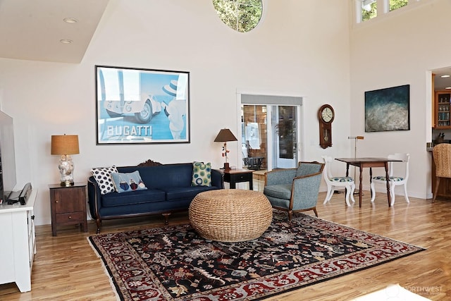 living area featuring baseboards, a high ceiling, and light wood-style flooring