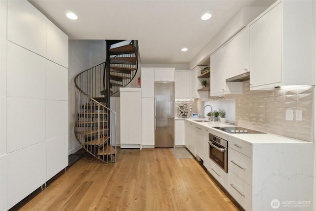 kitchen featuring a sink, open shelves, light countertops, under cabinet range hood, and appliances with stainless steel finishes