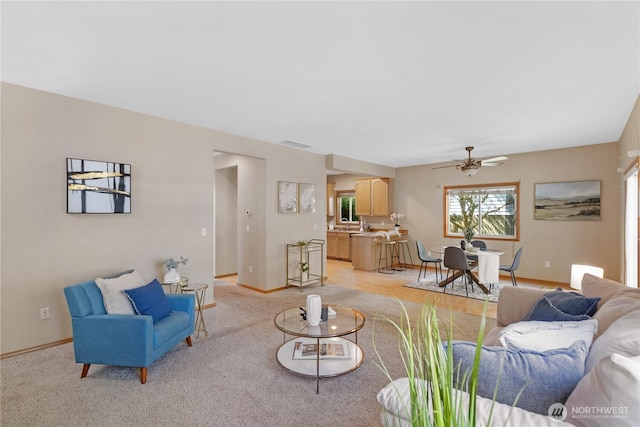 living room featuring visible vents, light carpet, baseboards, and ceiling fan