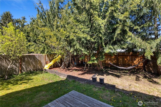 view of yard with a fenced backyard, a playground, and a deck