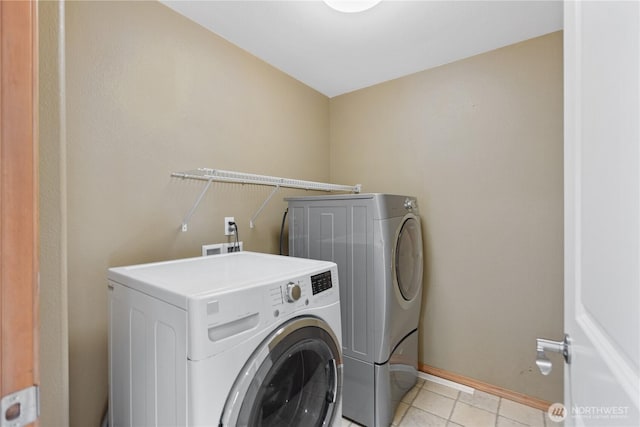 laundry area featuring light tile patterned floors, washing machine and clothes dryer, baseboards, and laundry area