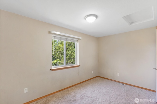 spare room with attic access, baseboards, carpet flooring, and visible vents