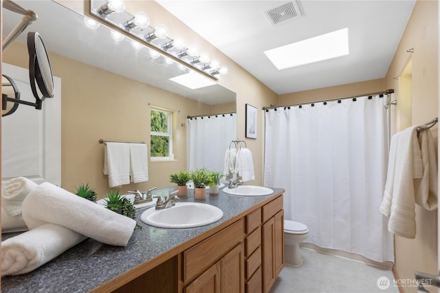 full bath featuring a skylight, visible vents, a sink, and double vanity