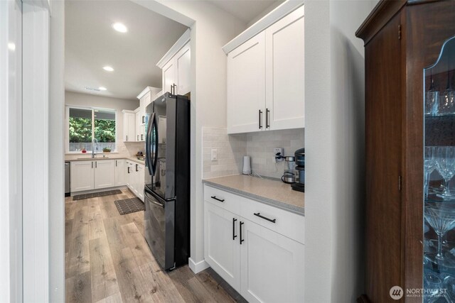 8852 N 5th St, Ridgefield, WA 98642 - kitchen with a sink, freestanding refrigerator, white cabinetry, decorative backsplash, and light wood-style floors