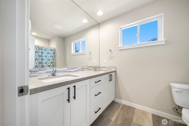 8852 N 5th St, Ridgefield, WA 98642 - bathroom with a sink, toilet, wood finished floors, double vanity, and baseboards
