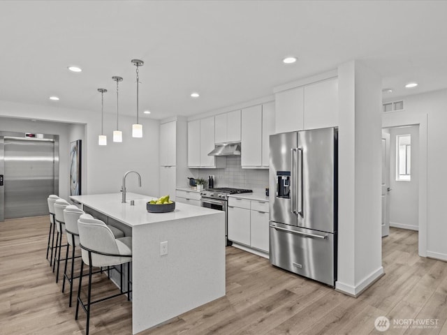 15528 NE 15th Pl Unit 201, Bellevue, WA 98007 - kitchen featuring premium appliances, elevator, under cabinet range hood, a kitchen bar, and light countertops