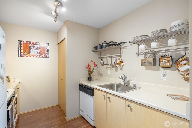 kitchen with white dishwasher, a sink, light wood-style floors, light countertops, and range
